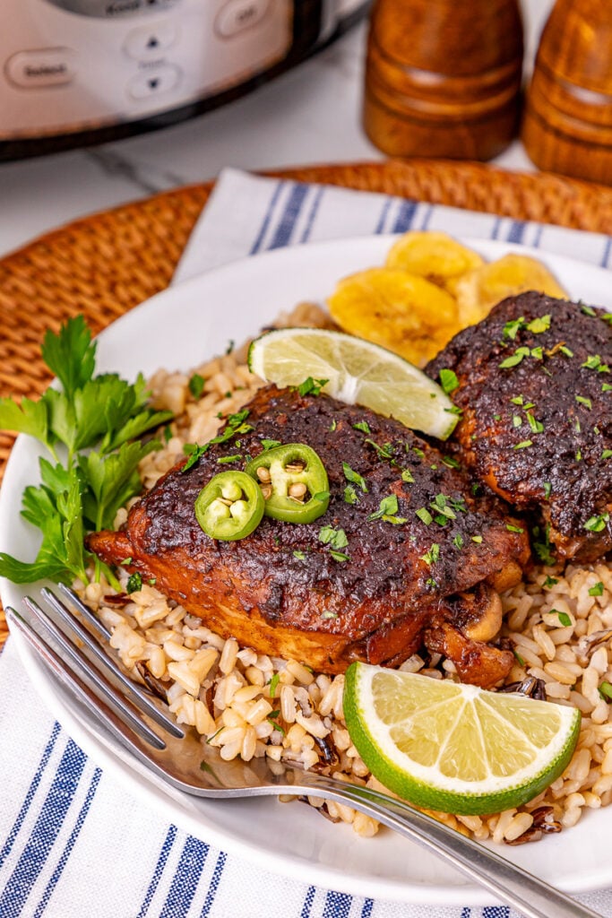Crockpot jerk chicken thighs served on a plate with rice.