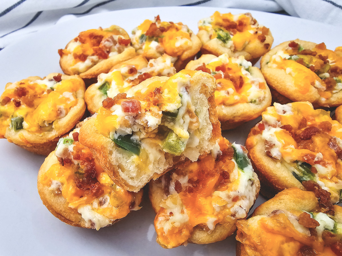 Side view of jalepeno and bacon bites on a white plate.