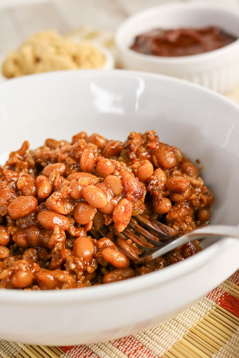 Cowboy baked beans served in bowl with a fork on the side.