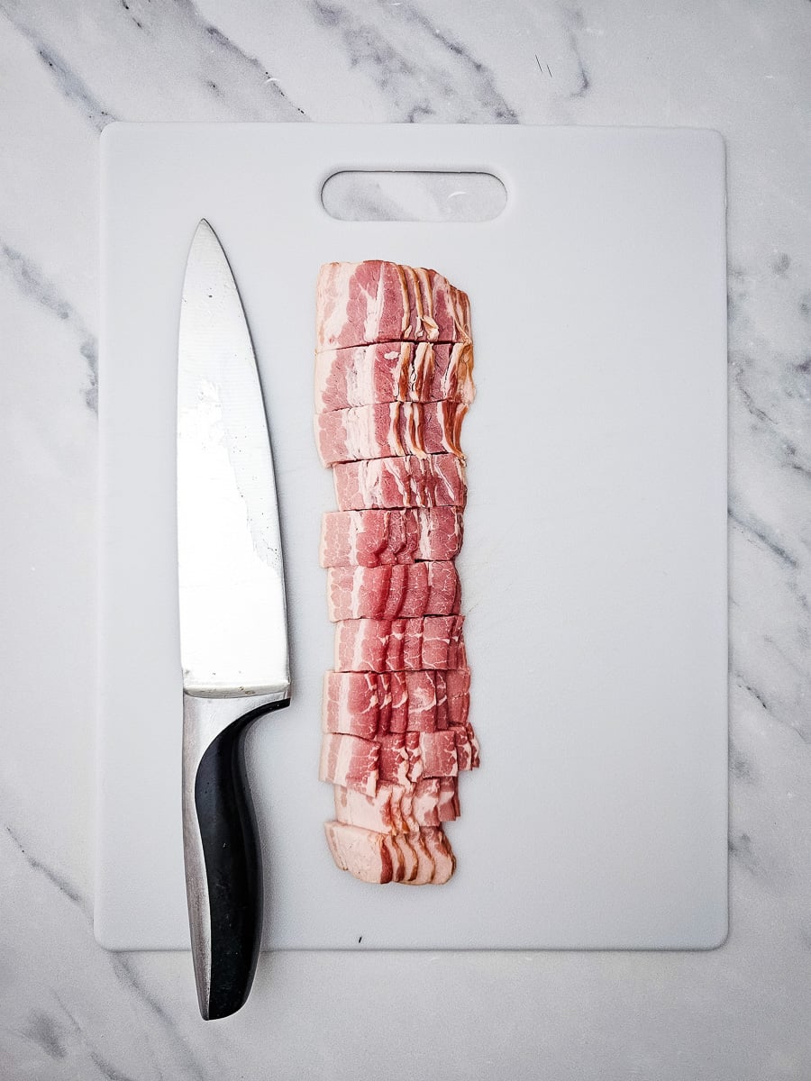 Chopped bacon on cutting board with knife.