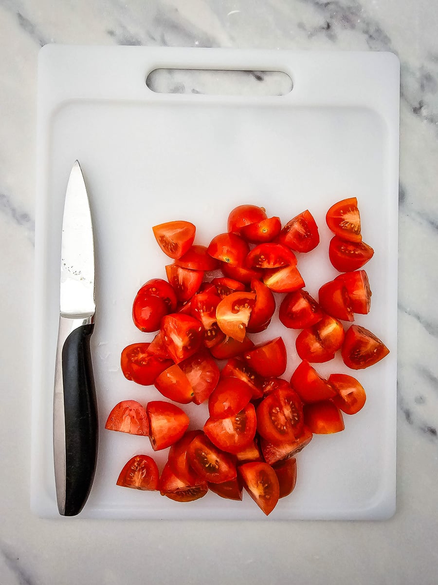 Diced tomatoes on cutting board with knife.