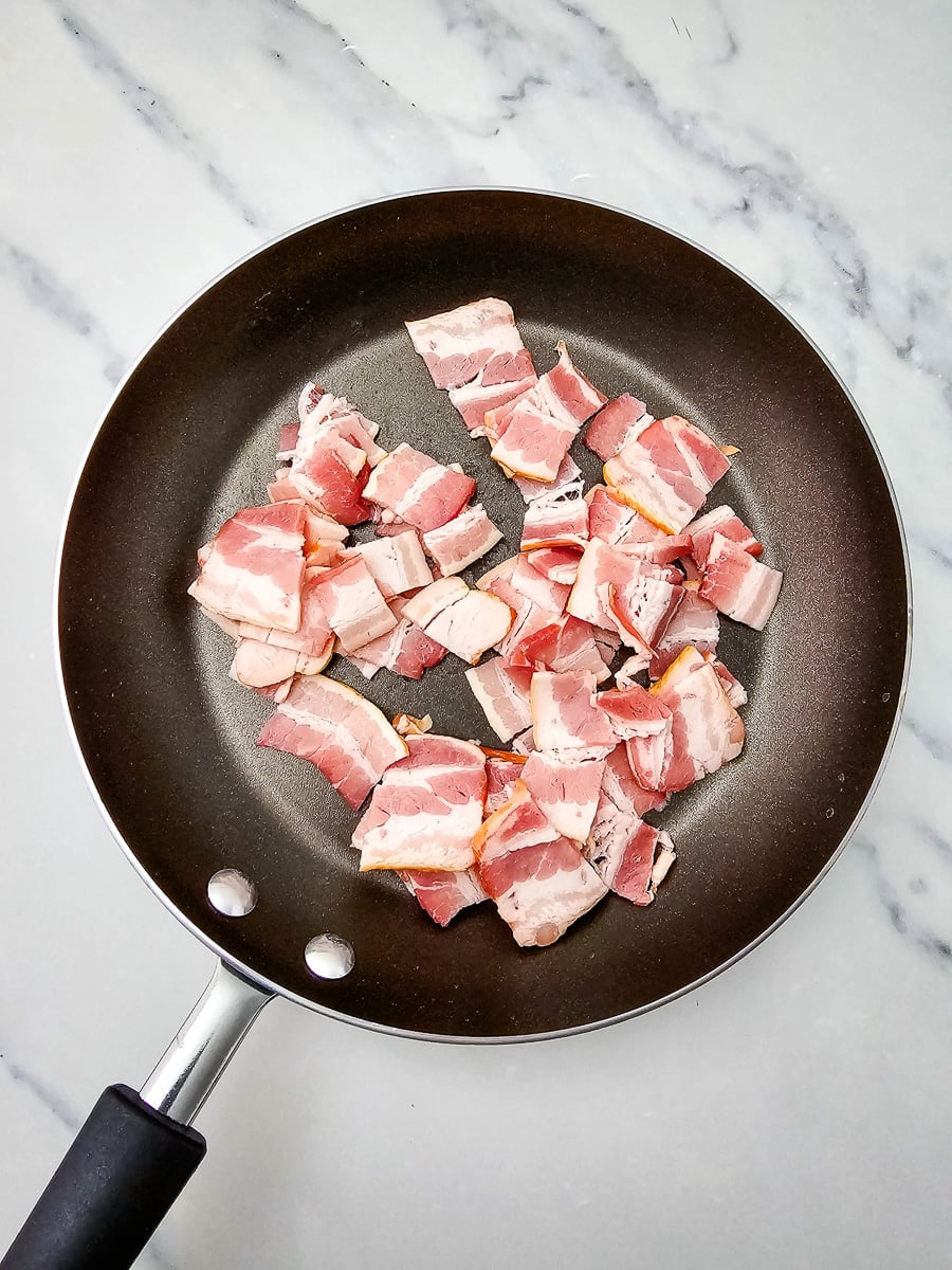 Chopped bacon cooking in skillet.