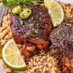 Crockpot jerk chicken thighs with brown rice on a plate.