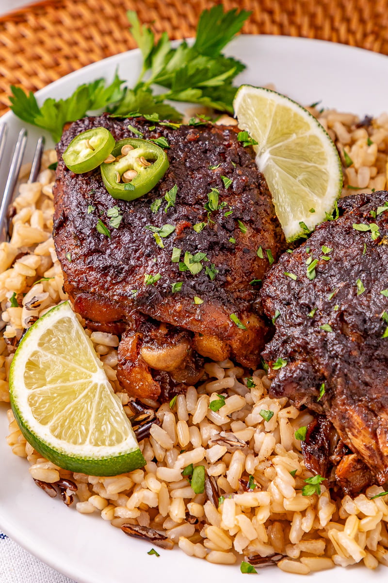 Crockpot jerk chicken thighs with brown rice on a plate.