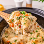 Scoop of chicken and dumplings held over slow cooker.