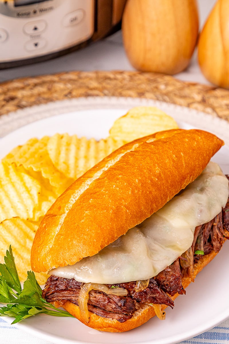 French dip sandwiches on a plate with potato chips.