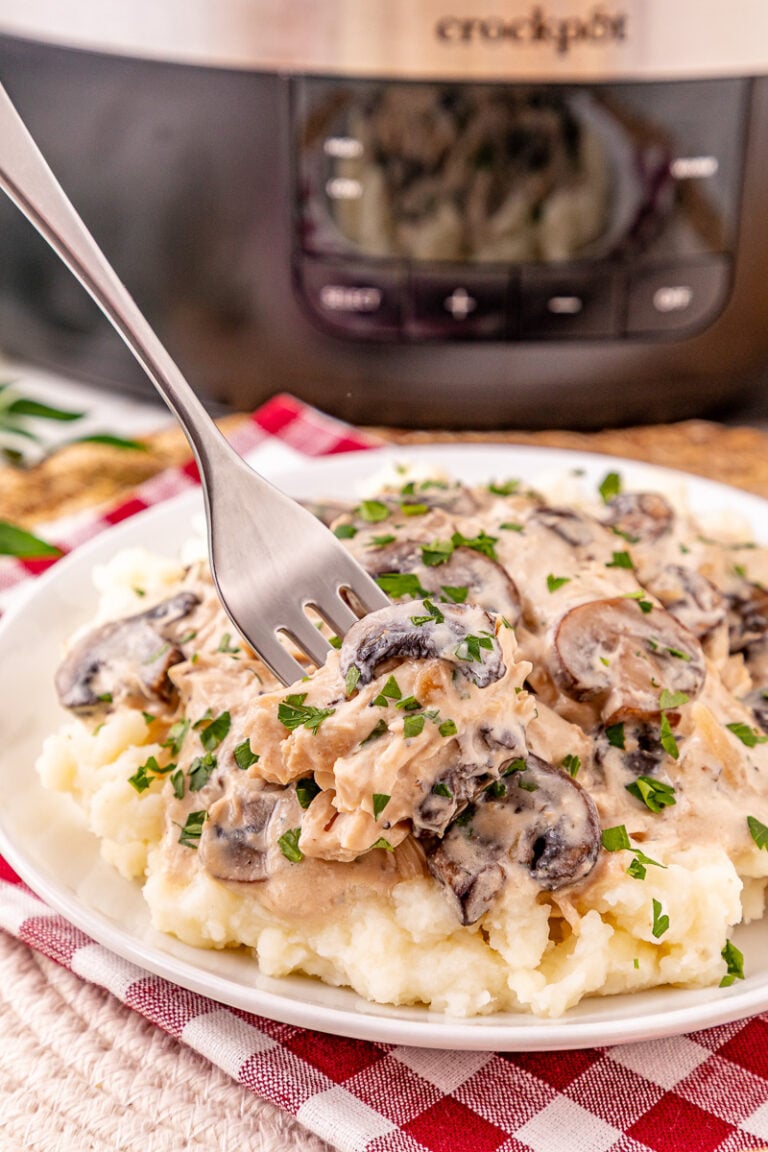 Crockpot creamy mushroom chicken served on a plate with mashed potatoes.