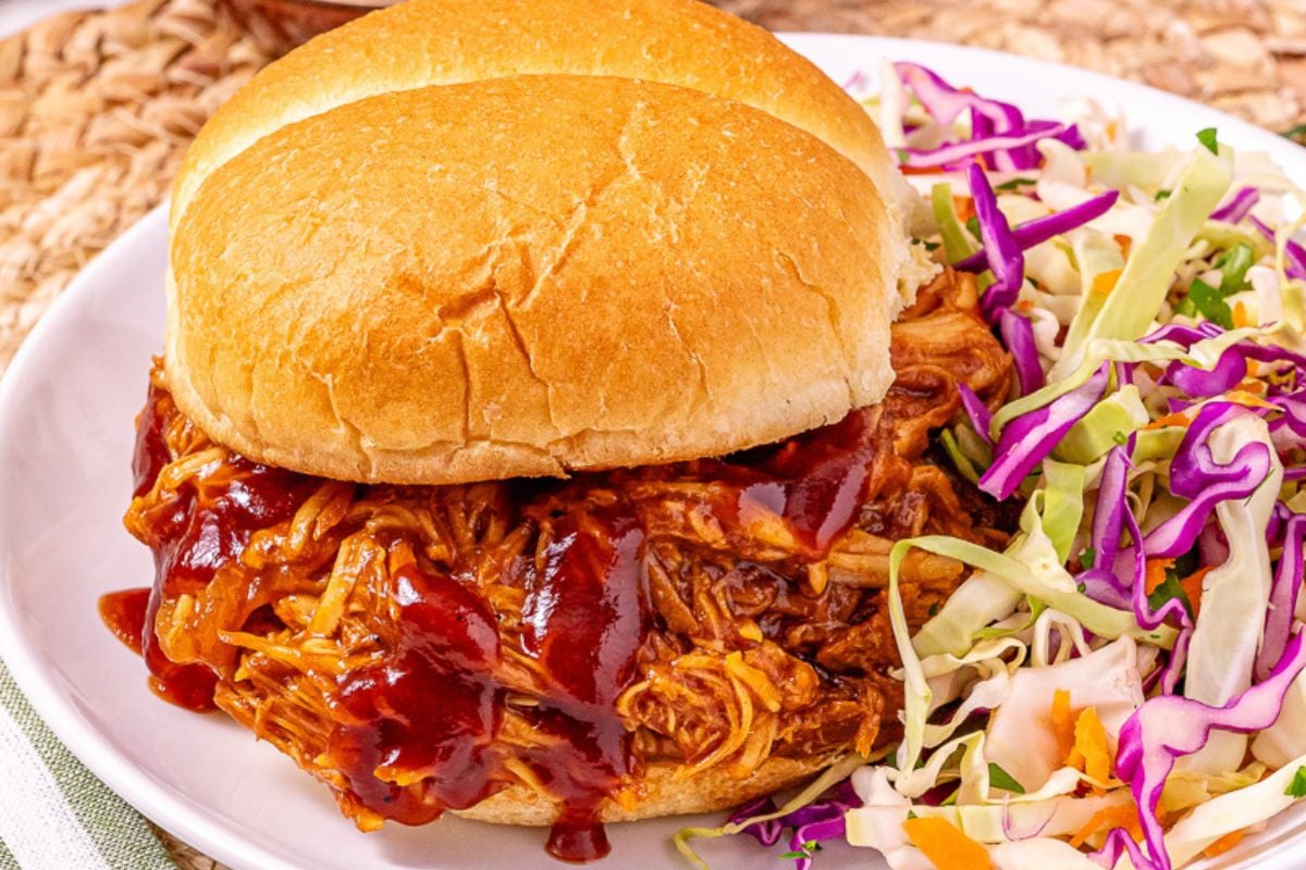 BBQ pulled chicken served on a bun with coleslaw on the side.