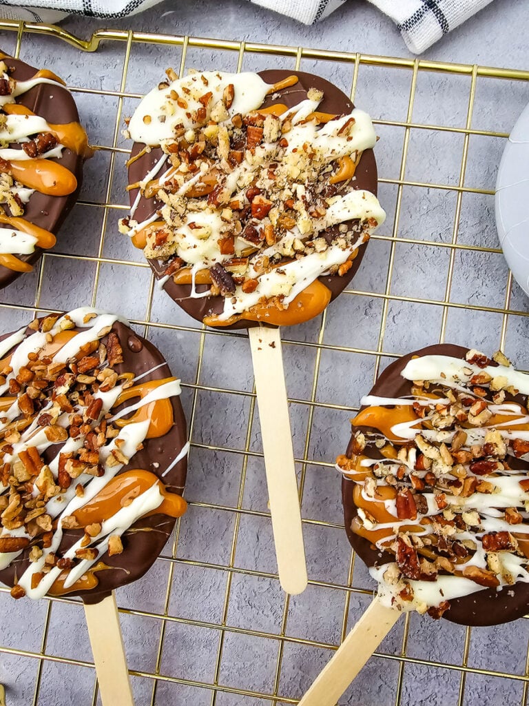 Chocolate-covered caramel apple slices on wire cooling rack.