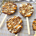Caramel apple slices with chocolate on wire cooling rack.