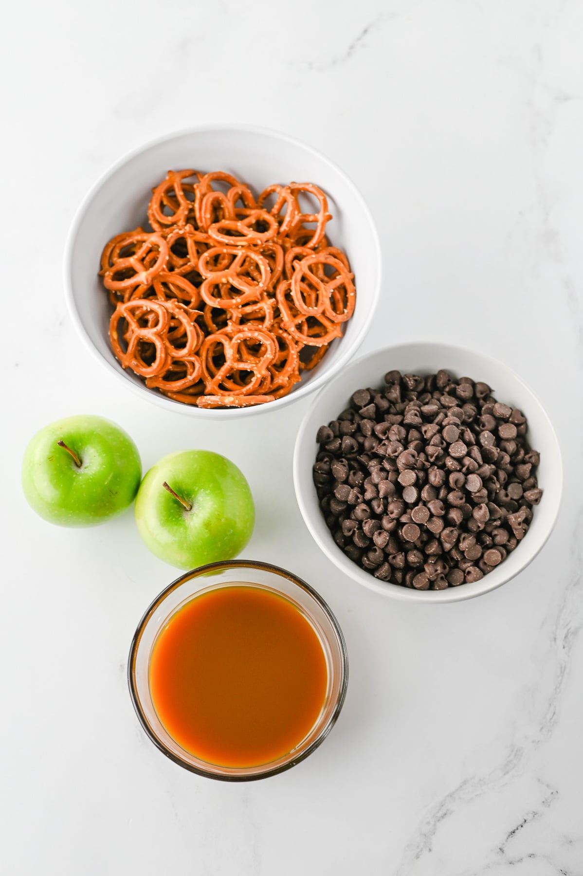 Ingredients for caramel apple bark in small bowls on counter in preparation for the recipe.
