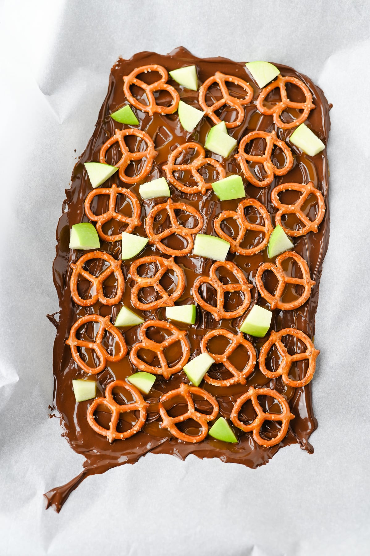Pretzels and apples are added to the top of the melted chocolate.