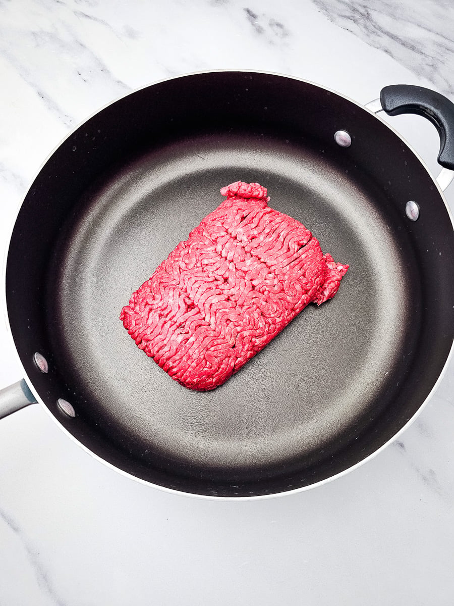 Ground beef cooking in skillet.