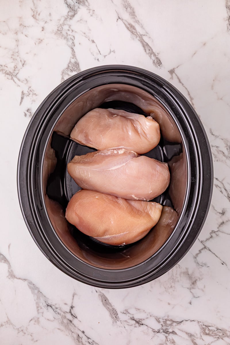 Boneless chicken breasts in bottom of crockpot.