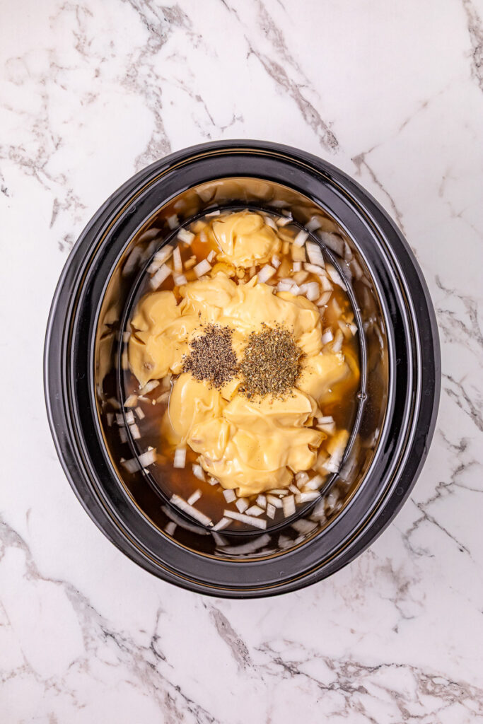 Cream of chicken soup and seasoning are added to the crockpot.