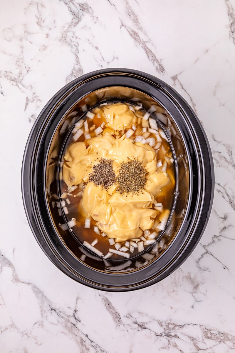 Cream of chicken soup and seasoning are added to the crockpot.