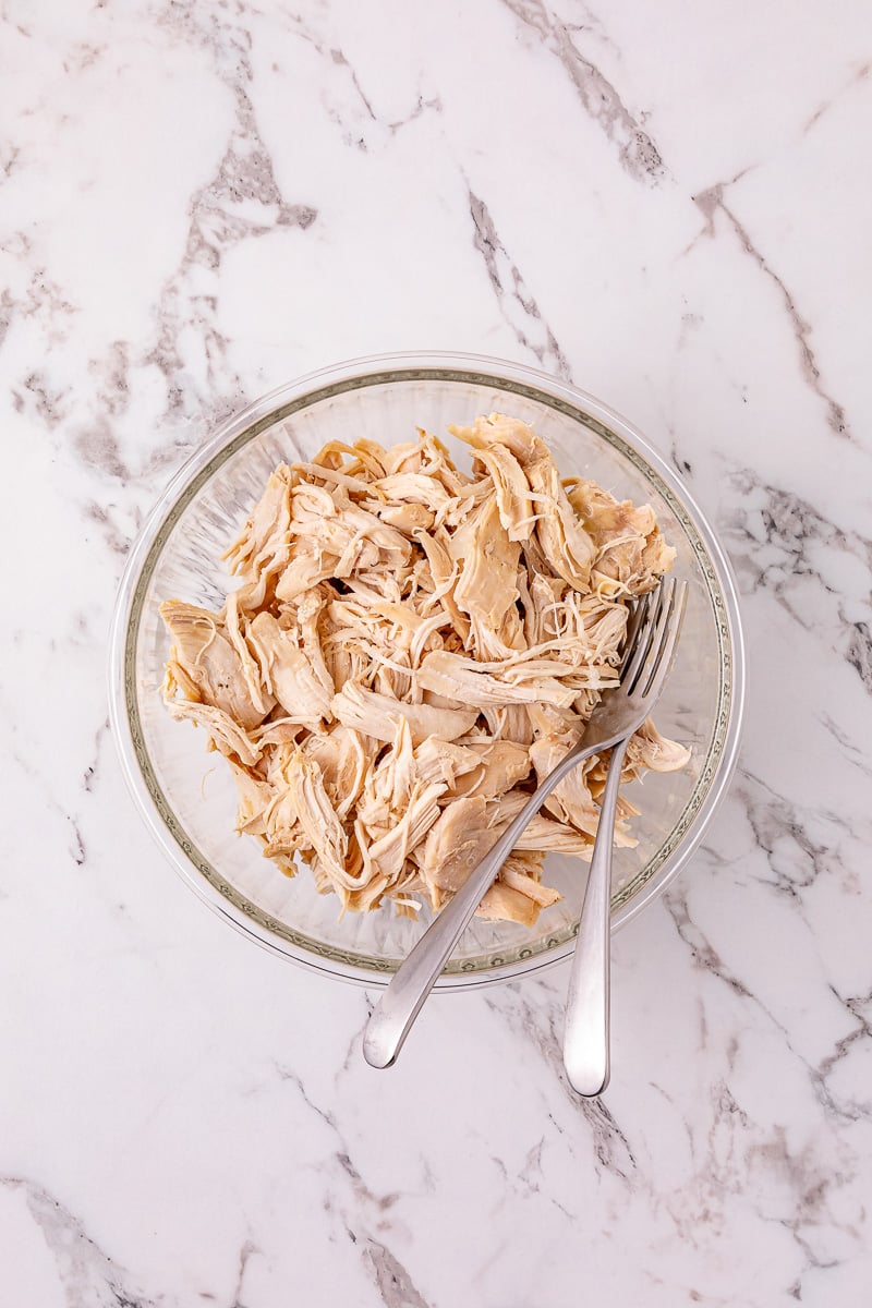 Chicken is removed and shredded ina small bowl.