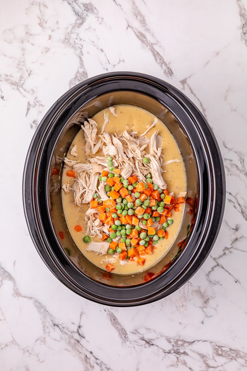 Shredded chicken and peas and carrots are returned to the crockpot.