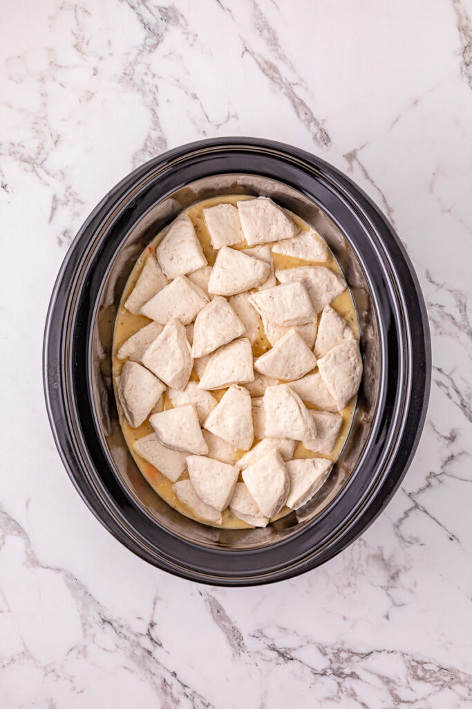 Biscuit pieces are added to the crockpot.