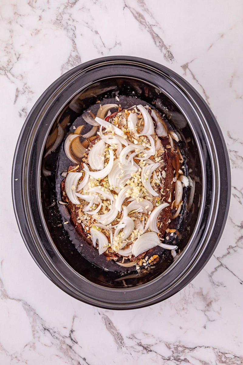 Onion mixture is added to the top of the roast beef in crockpot.