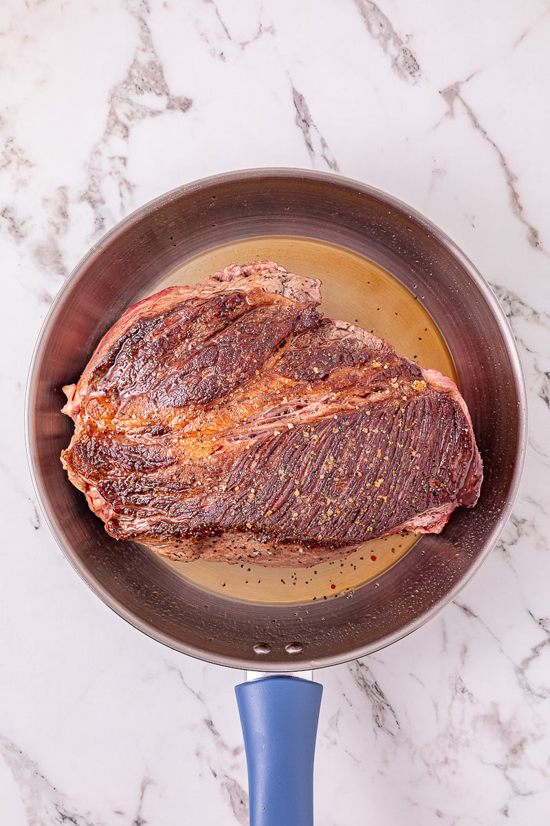 Roast beef searing in skillet.