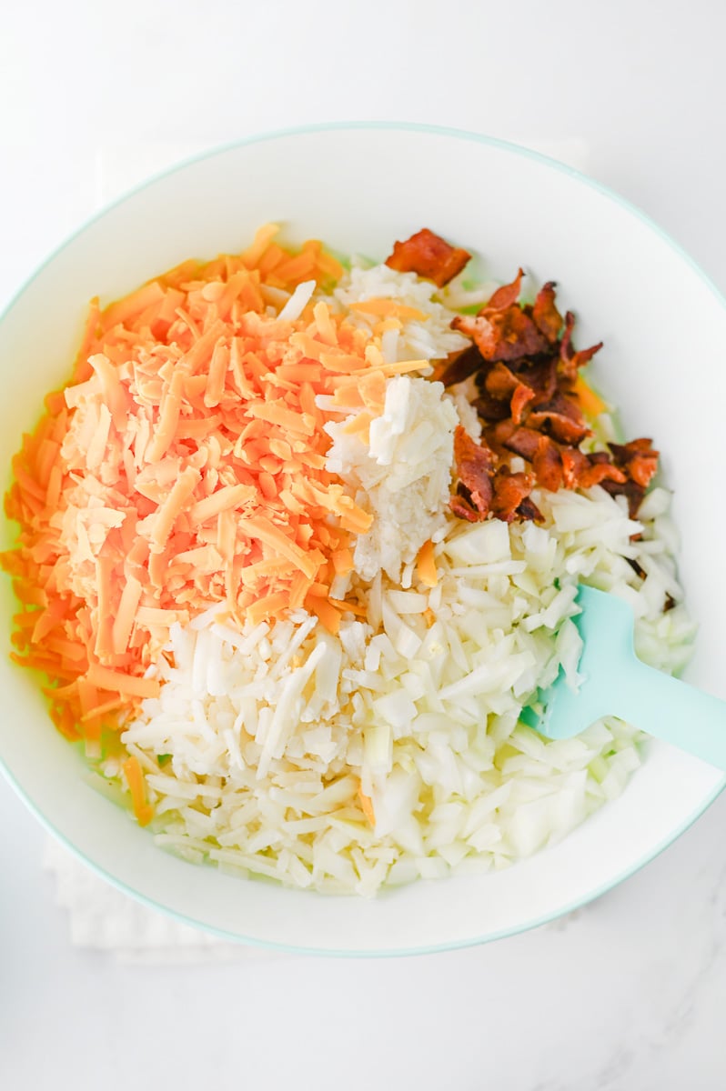Hashbrown, cheese, bacons and onions are added to mixing bowl.
