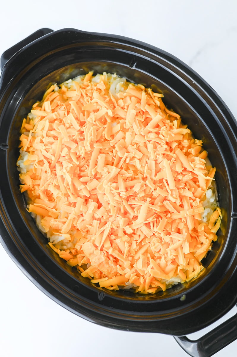 Cheese is added to the top of the crockpot.