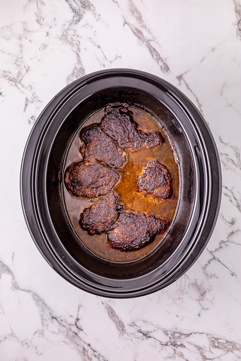 Mixture is poured over chicken thighs in slow cooker.