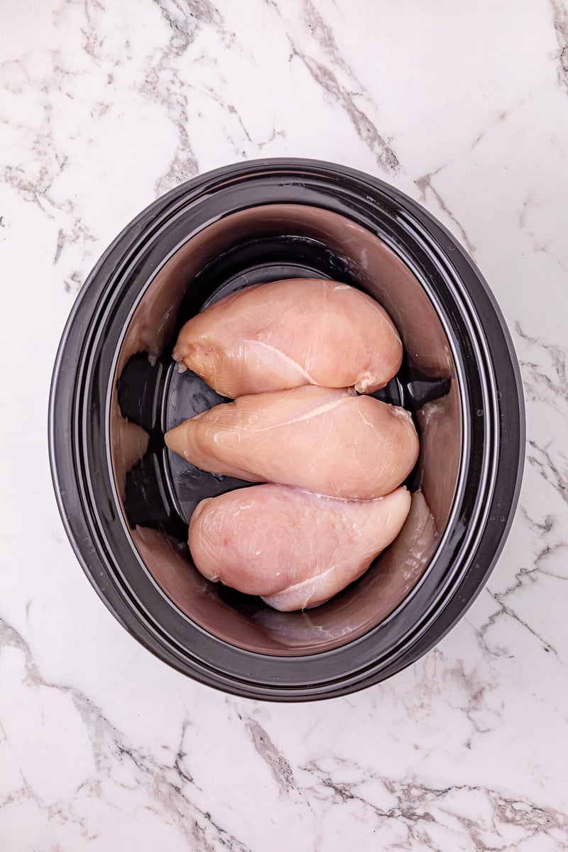 Chicken breasts are placed in the bottom of crockpot.