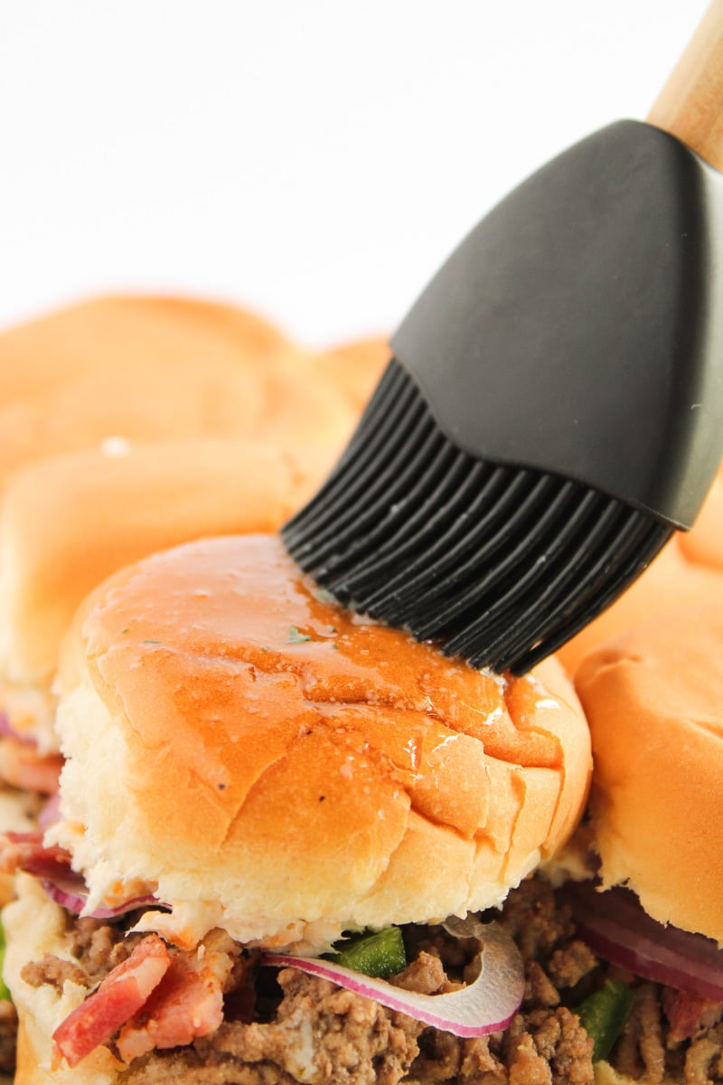 Butter mixture is spread on top of buns.