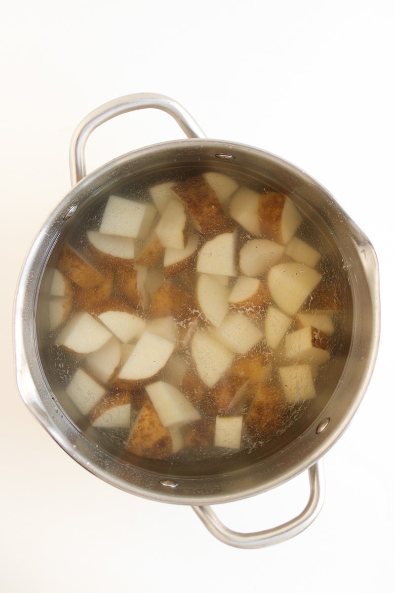 Cut potatoes in boiling water in pot on stove.