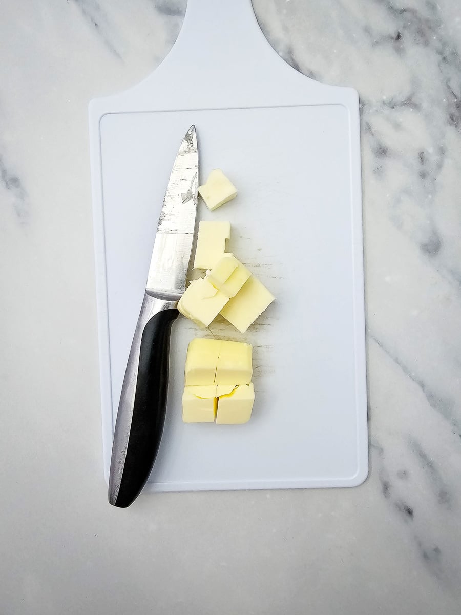 Sliced butter on cutting board with knife.