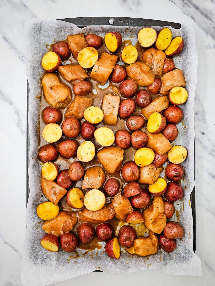 Chicken and potato mixture is added to the parchment lined baking sheet.