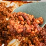 Cowboy baked beans scooped up on serving spoon.