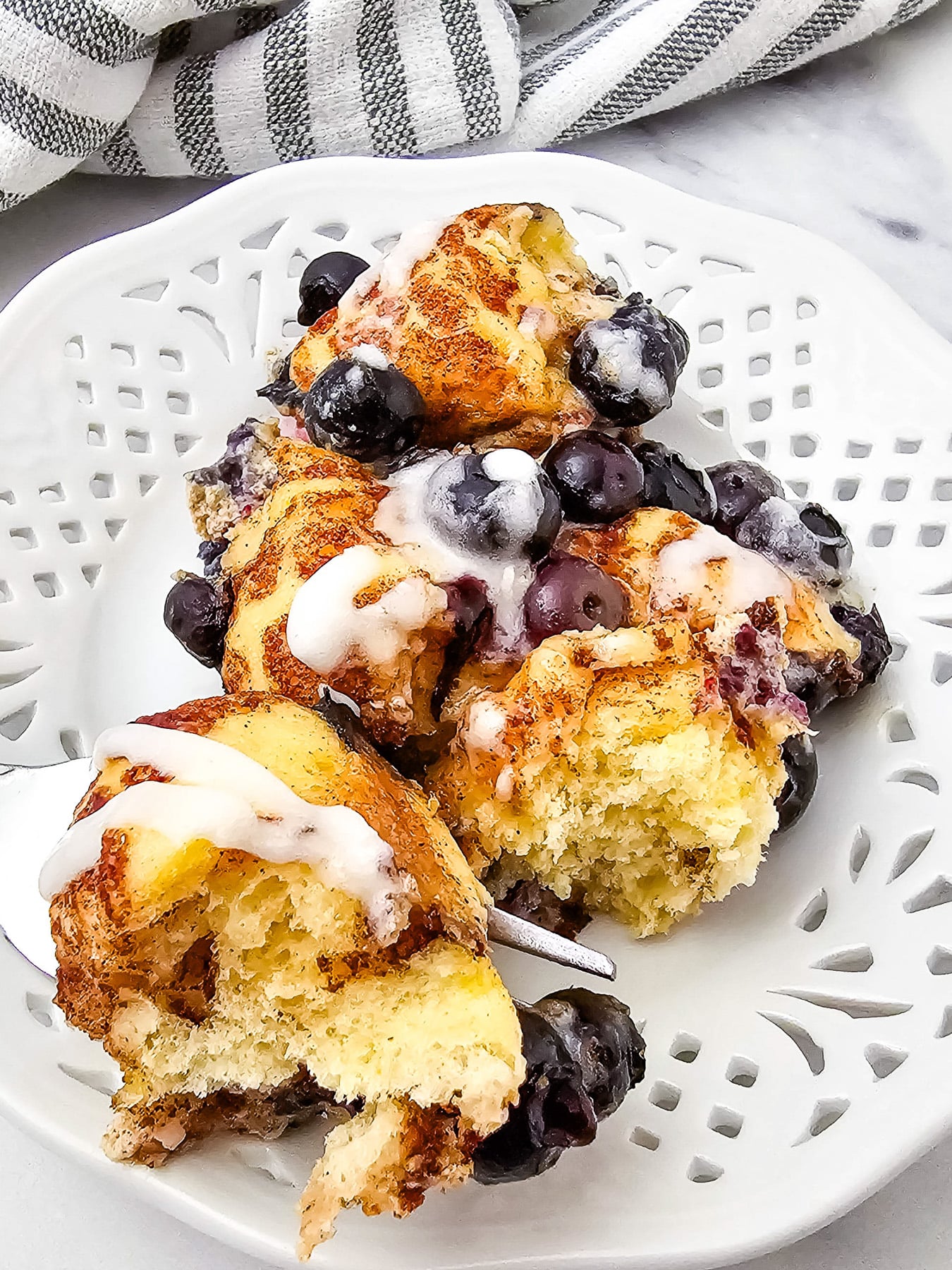 Blueberry cinnamon roll casserole served on a white plate.