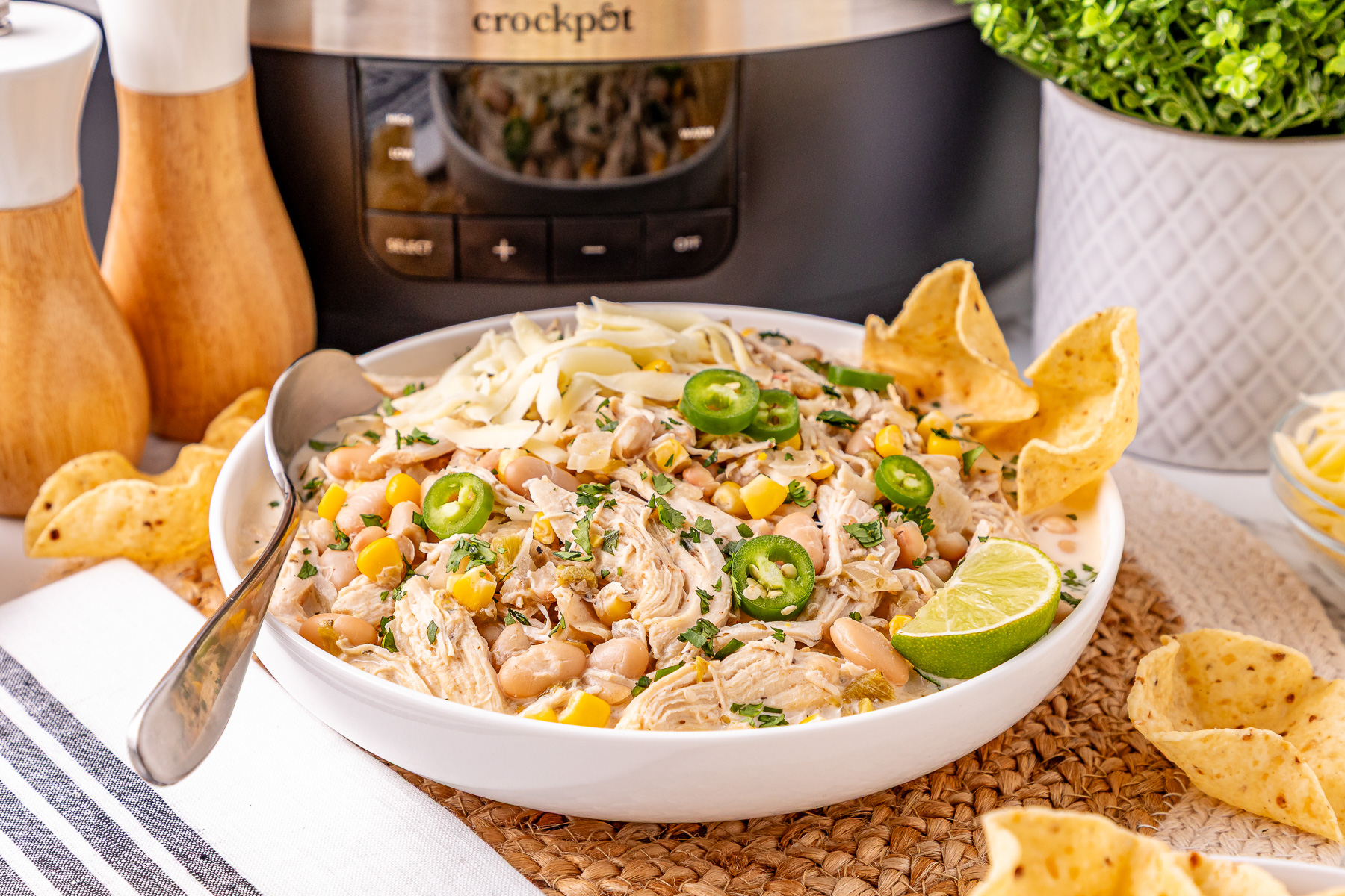 White chicken chili served in a white bowl with tortilla chips on the side.