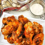 Crispy grilled buffalo chicken wings served on a plate for a football party.