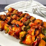 Grilled chicken and pineapple kabobs on a white plate.