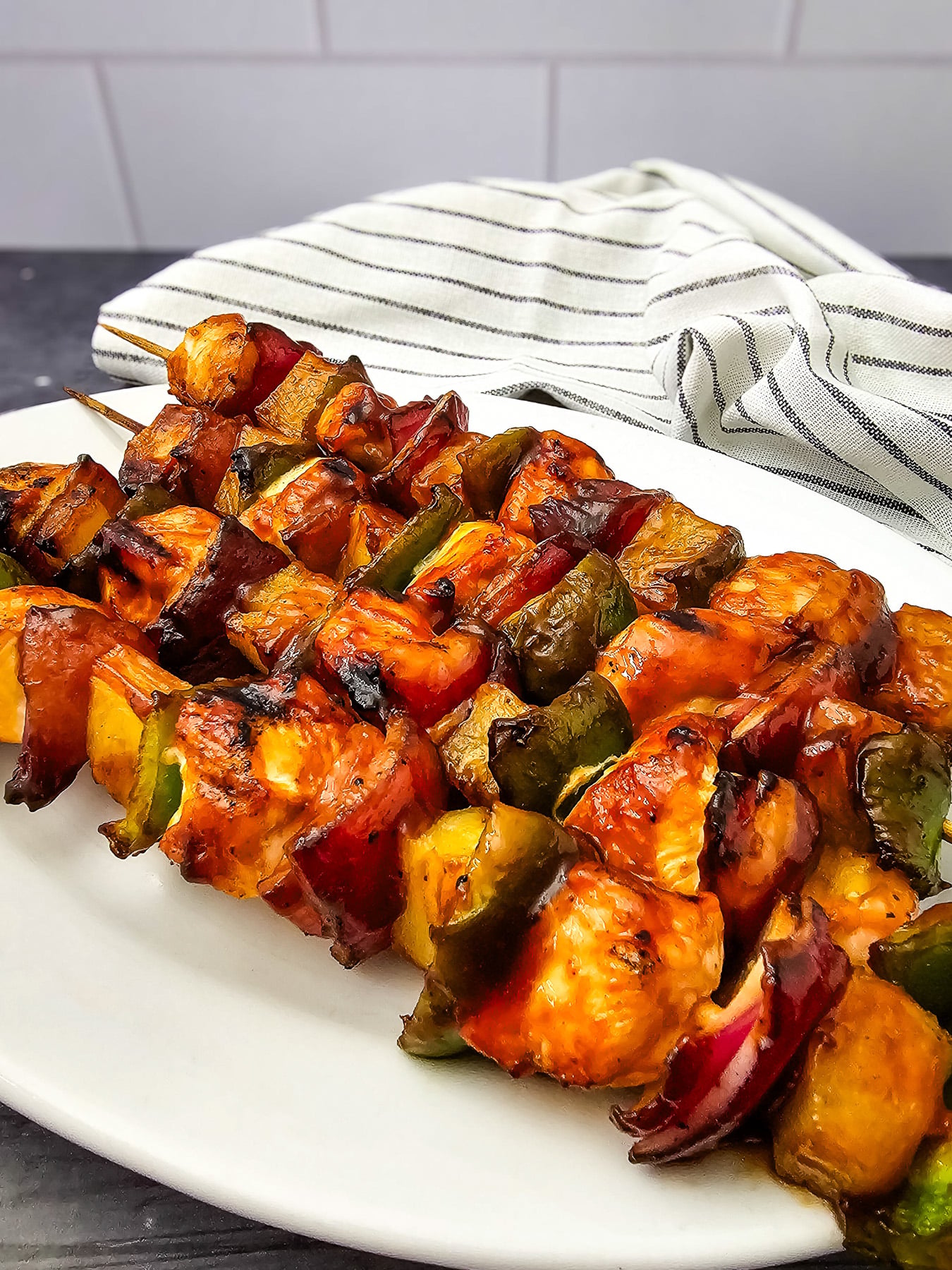 Grilled chicken and pineapple kabobs on a white plate.
