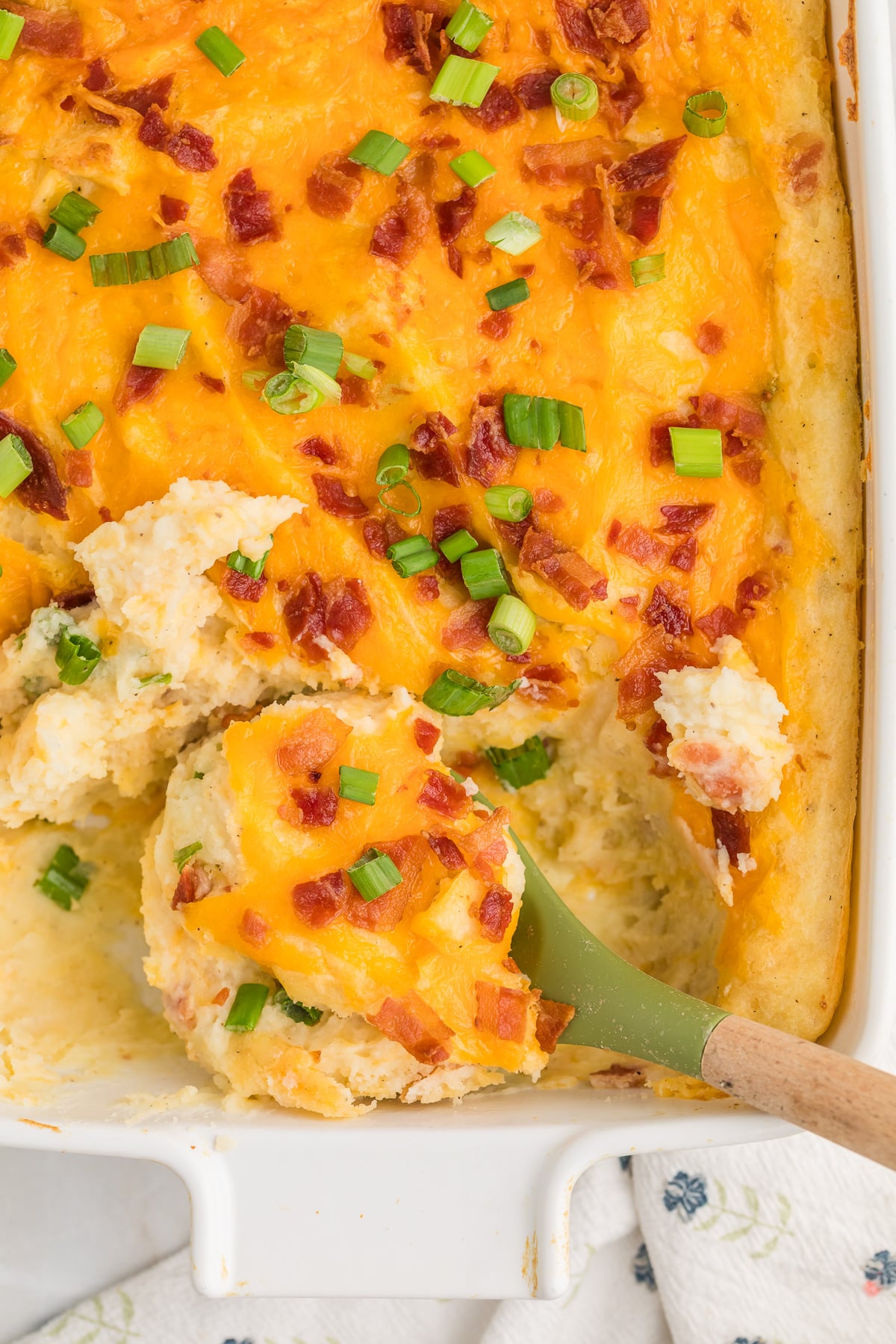 Twice baked mashed potato casserole in baking dish with a spoon.