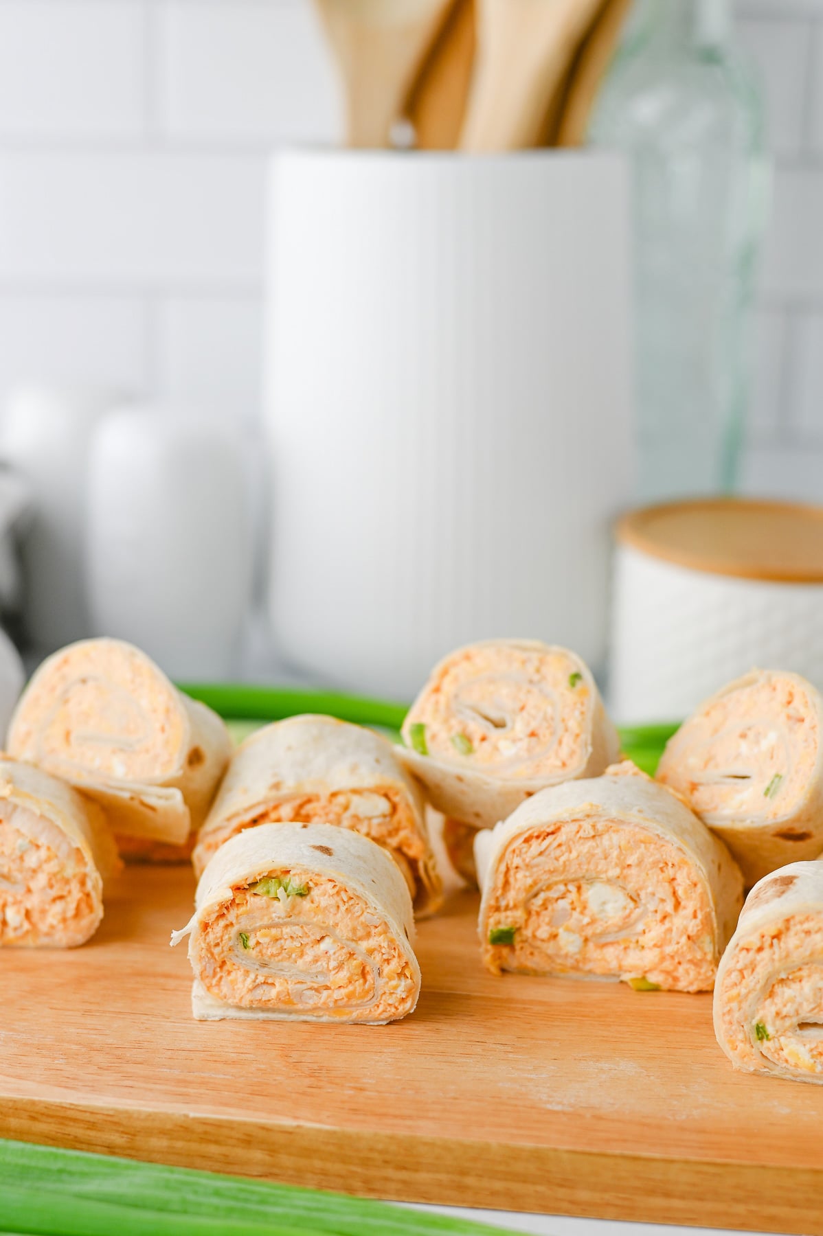Buffalo chicken pinwheels on wooden serving board.