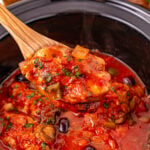 Crockpot chicken cacciatore scooped up in spoon.