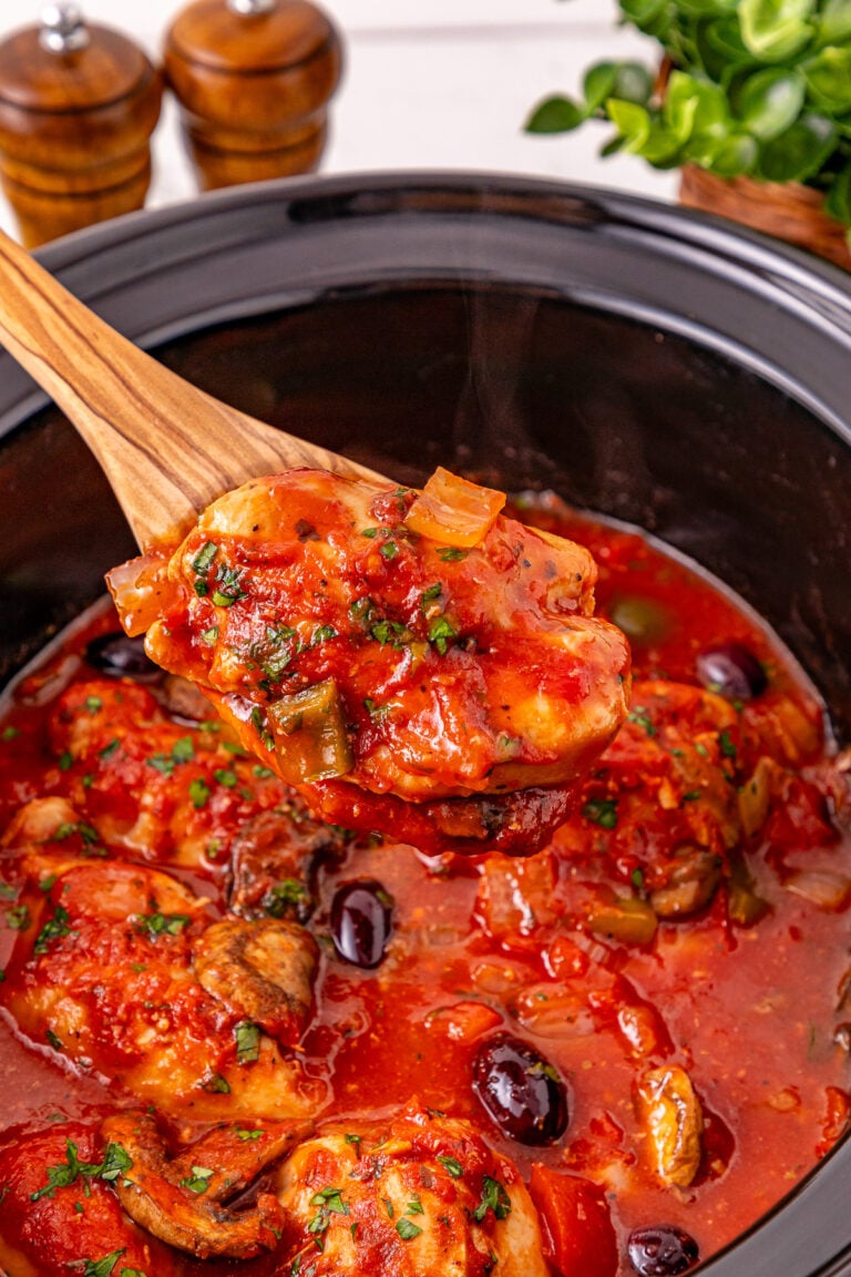 Crockpot chicken cacciatore scooped up in spoon.
