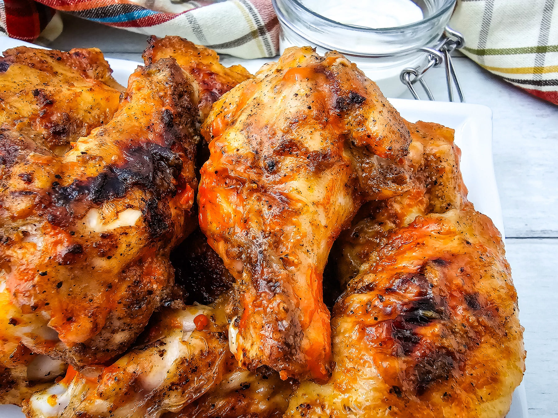 Side view of grilled chicken wings served on a white plate.