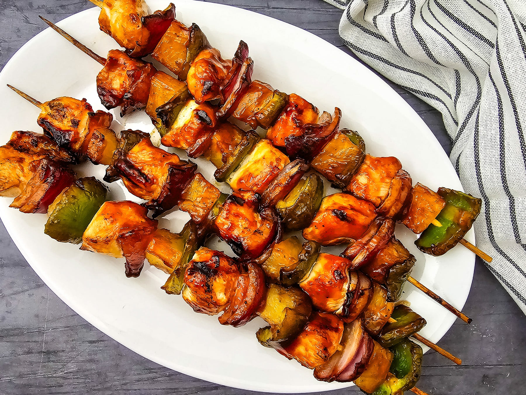 Chicken and pineapple kabobs on a white plate.