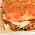 Pulled pork sliders with Hawaiian rolls on wooden serving board.