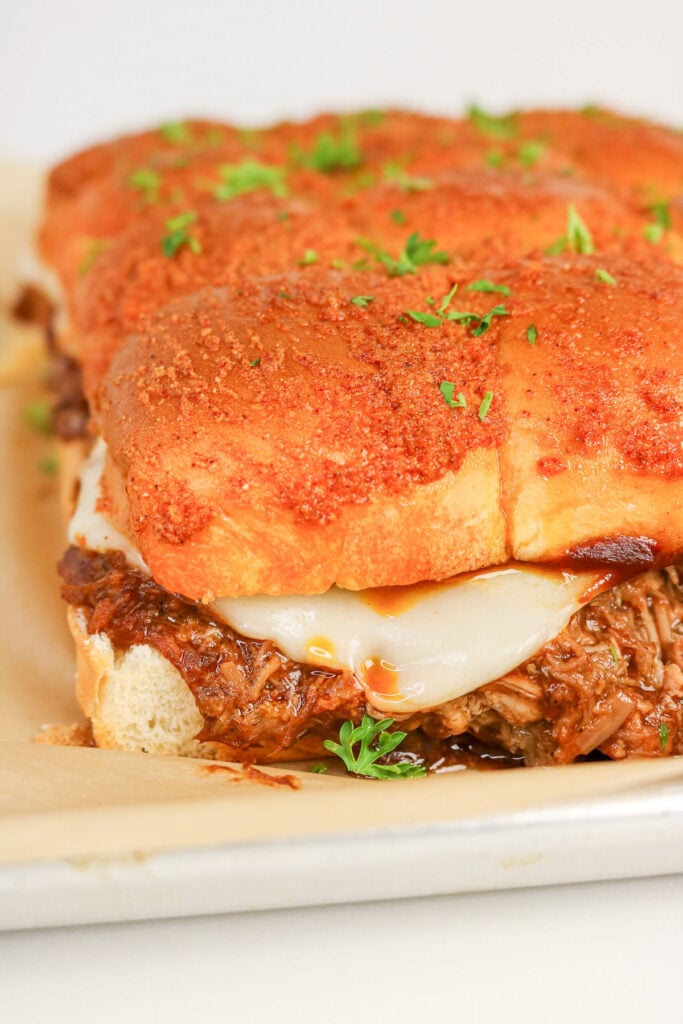 Pulled pork sliders on a wooden serving board.