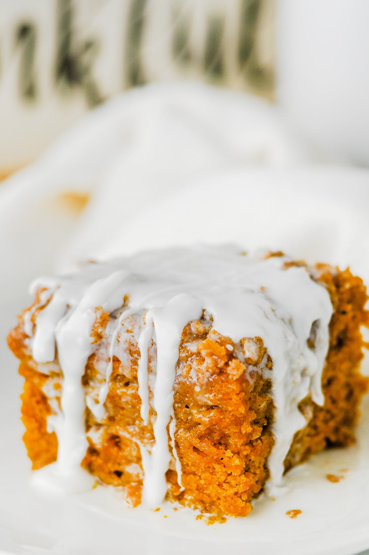 Pumpkin coffee cake with glaze served on a white plate.
