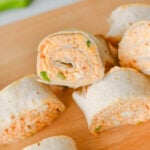 Buffalo chicken pinwheels on wooden serving board.