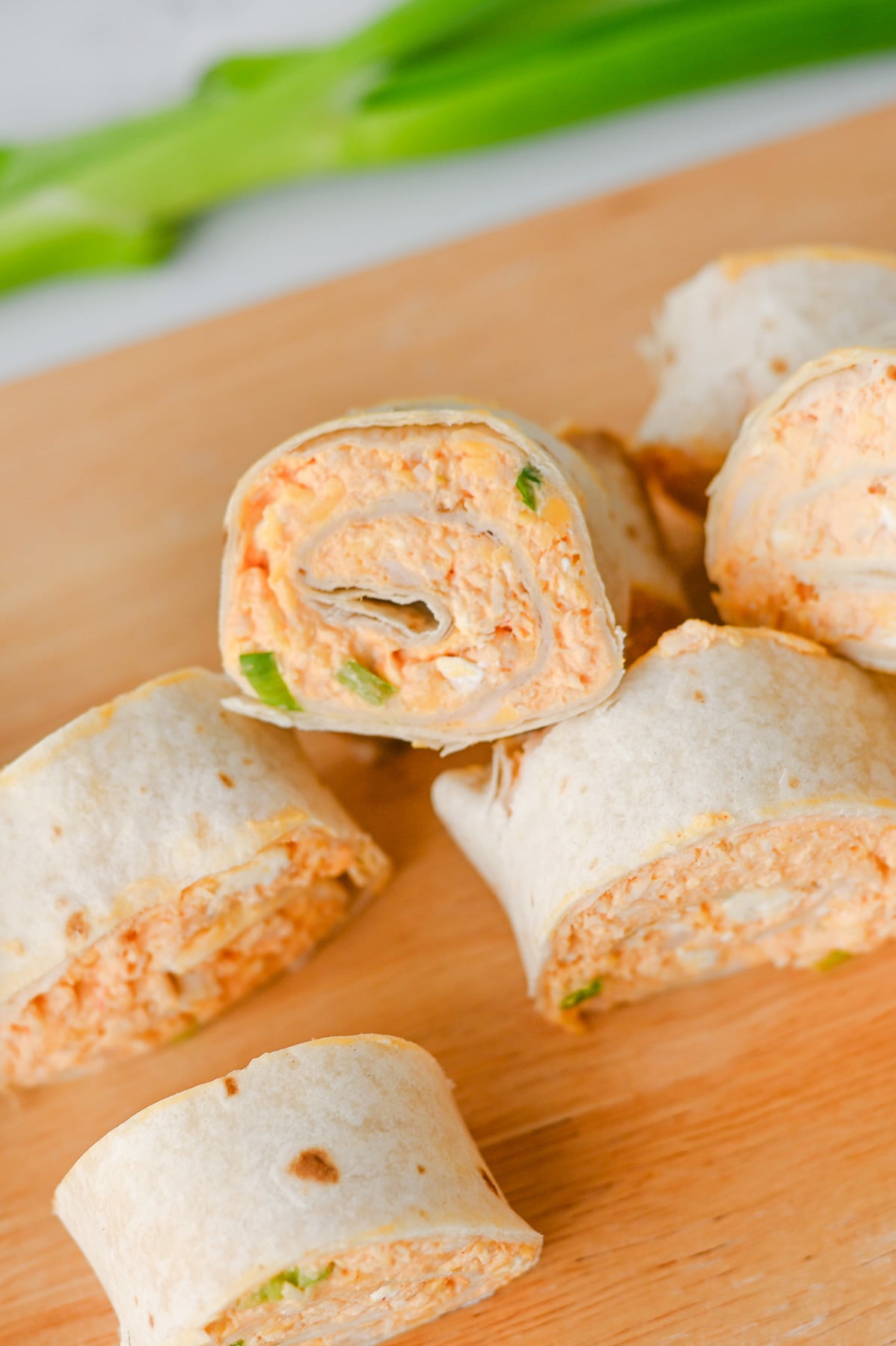 Buffalo chicken pinwheels on wooden serving board.